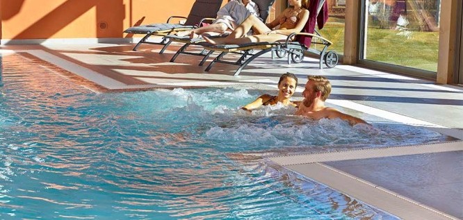 Paar entspannt bei Sonnenschein im Schwimmbad von Michels Wohlfühlhotel, Rheinland-Pfalz, Vulkan-Eifel, Schalkenmehren  