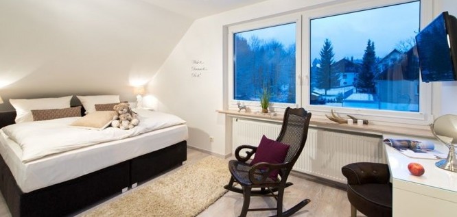 Schlafzimmer mit Doppelbett und Schaukelstuhl im Wellness Resort Romantischer Winkel im Harz, Bad Sachsa