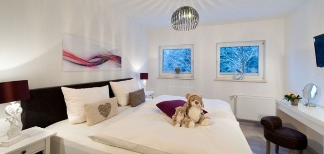 Schlafzimmer mit Doppelbett und Kuscheltieren im Wohlfühl-Appartement des Wellness Resort Romantischer Winkel im Harz, Bad Sachsa