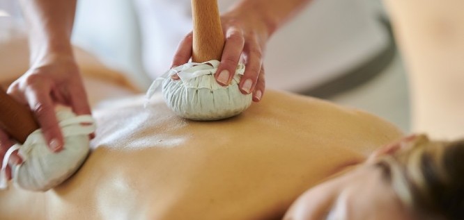 Frau genießt wohltuende Kräuterstempelmassage – Schüle's Gesundheitsresort & Spa – Allgäu | Bayern