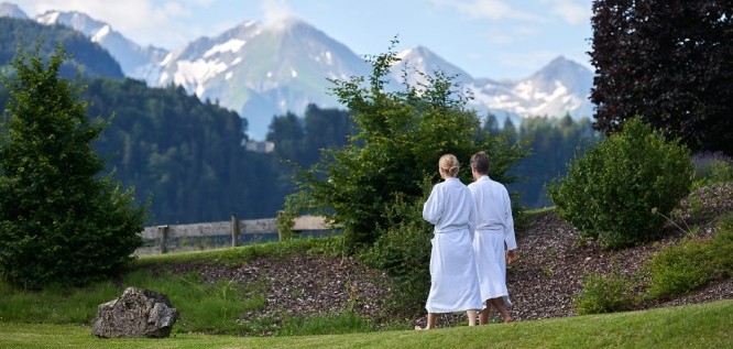 Ein Paar im Bademantel spaziert entspannt durch den Garten – Schüle's Gesundheitsresort & Spa |Allgäu | Bayern  