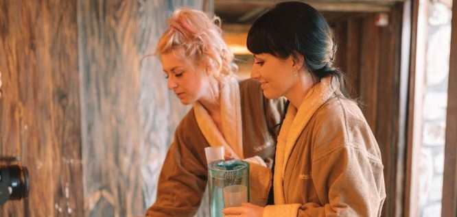 Frauen nehmen sich an der Wasserstation ein Wasser – Wellnesshotel Seeschlößchen | Privat-SPA & Naturresort