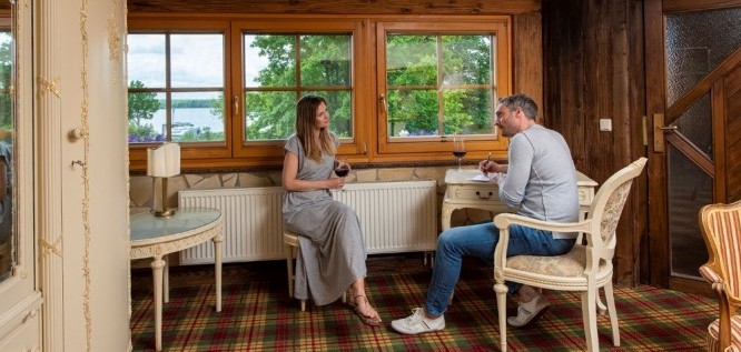 Pärchen trinkt in Schloss Suite ein Glas Wein und schreibt Postkarte - Wellnesshotel Seeschlößchen | Privat-SPA & Naturresort – Niederlausitz/Brandenburg